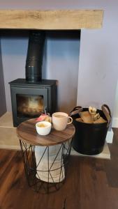 a stove and a table with two cups on it at Gardeners Cottage Apartment in Tyberton