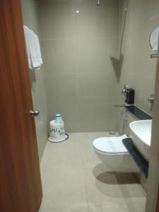 a white bathroom with a toilet and a sink at Shreeja Central in Bhawānipatna