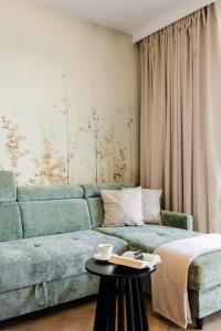 a living room with a green couch and a table at Apartament Harmonia Baltic in Sarbinowo