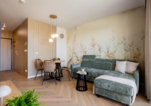 a living room with a green couch and a table at Apartament Harmonia Baltic in Sarbinowo