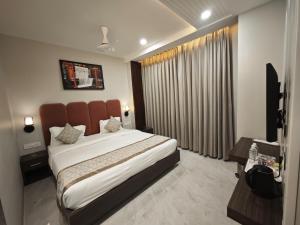 a bedroom with a large bed and a television at Hotel Kaashika in Varanasi +12 photos