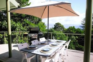 a table with an umbrella and a grill on a deck at Sanctuary Spaces - Wategoes Beach Shack in Byron Bay