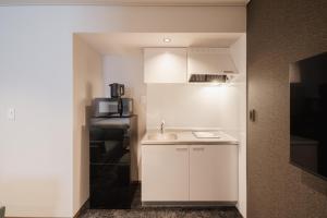 a white kitchen with a sink and a refrigerator at Hotel SHUTEC in Kagoshima