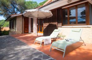 a patio with two chairs and an umbrella at Villa Fornaci - Marina di Campo in Marina di Campo