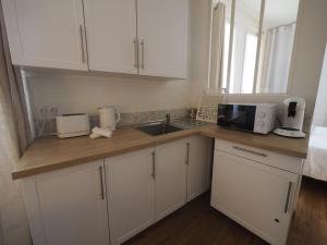 a kitchen with white cabinets and a sink at Le Picaflor YourHostHelper in Hyères