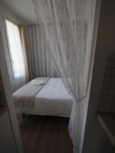 a bedroom with a bed with a white curtain at Le Picaflor YourHostHelper in Hyères +6 photos