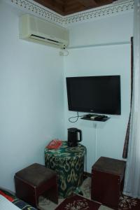 a room with a tv on a wall with a table and a stool at Sukhrob Barzu Hotel in Bukhara