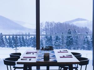 a dining room table with chairs and a large window at Furano Hotel 富良野ホテル in Furano