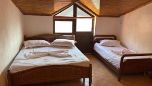 two beds in a small room with a window at Deda Apartaments in Shëngjin