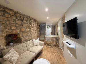 a living room with a couch and a stone wall at Le Petit Coin in Saintes