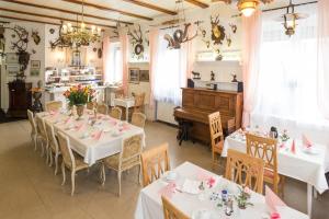 un comedor con mesas blancas y un piano en Hotel Moosbichl, en Múnich