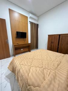 a bedroom with a bed and a flat screen tv at D & R House Syariah in Jagalan