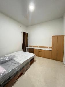 a bedroom with a bed and a wooden cabinet at D & R House Syariah in Jagalan