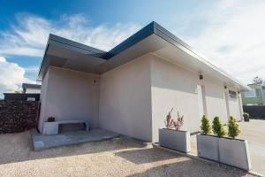 a white house with a blue roof and two plants at Apartmány Mahaus in Bojnice
