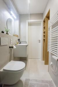 a white bathroom with a toilet and a sink at Apartmány Mahaus in Bojnice