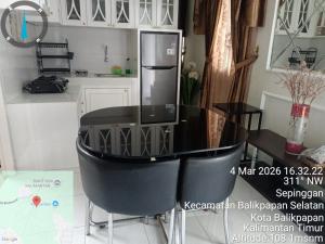 a kitchen with a black table and a refrigerator at Villa IDR Grandcity in Balikpapan