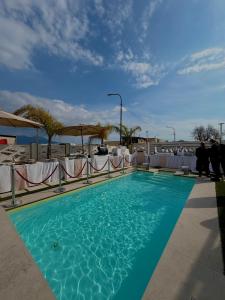 a swimming pool with blue water and white tables at Hotel Daytona Palace in Casoria