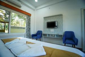 a bedroom with a bed and two blue chairs at Jai Ganesha Resort in Chālsa Mahābāri