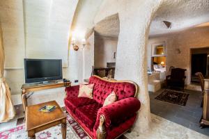 a living room with a red couch and a tv at CCR Cappadocia Cave Resort &Spa in Eskiömerler