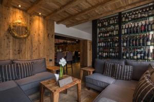 a room with two couches and a shelf of wine bottles at Hotel Marmolada in Corvara in Badia