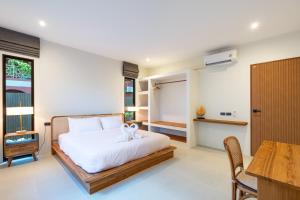 a bedroom with a bed and a desk and a table at Siva Pool Villa in Chaloklum