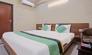 a bedroom with a large white bed with green pillows at Hotel Rama Hindustani in Jaipur