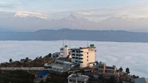 a building on a hill with mountains in the background at Pokhara Heights Resort Pvt Ltd in Pokhara