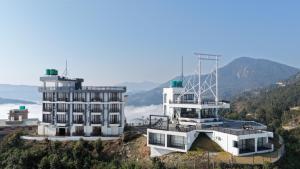 a building on a hill with mountains in the background at Pokhara Heights Resort Pvt Ltd in Pokhara