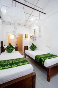 a room with two beds with green sheets at Glamour Mirissa in Mirissa