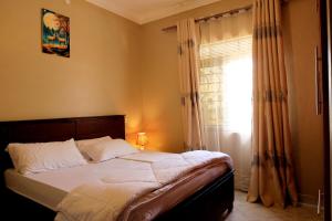 a bedroom with a bed and a window with curtains at Two-bedroom unit in Mubende Town in Mubende