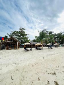 a beach with tables and umbrellas on the sand at Jeanette Beach Resort in Guinticgan