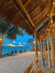 a beach with chairs and umbrellas and the ocean at Jeanette Beach Resort in Guinticgan