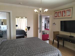 a bedroom with a bed and a desk and a television at Camdale Guesthouse in Cape Town