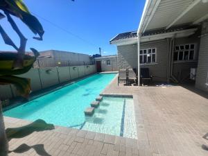 a swimming pool in front of a house at Khans Residence in Gqeberha