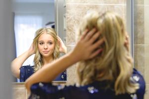 a woman brushing her hair in front of a mirror at Tótündér Vendégház in Levelek