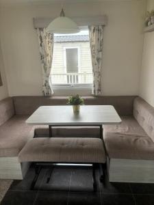 a dining room with a table and benches and a window at Beach Retreats, Romney Sands, Parkdean Resorts in Greatstone +13 photos