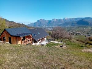 a house on a hill with mountains in the background at Chalet du Mont Granier in Apremont