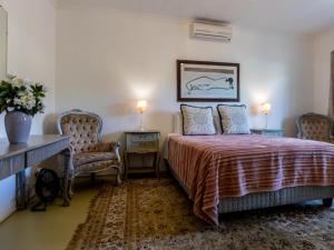 a bedroom with a bed and a desk and two chairs at Julie's Cottage in Riebeek-Kasteel