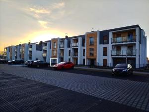 a row of buildings with cars parked in a parking lot at Słoneczny Apartament Karpicko in Karpicko +3 photos