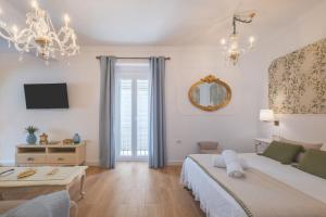 a white bedroom with a bed and a mirror at Palacete de La Alameda - Adults Only- in Cádiz