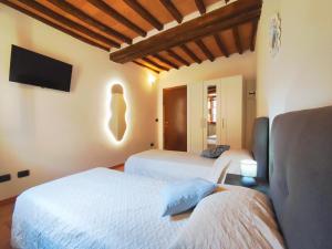 a bedroom with two beds and a flat screen tv at Le Torri 3 San Gimignano in San Gimignano +3 photos