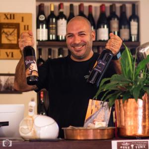 a man holding up a bottle of wine at Locanda dell Angelo in Piacenza
