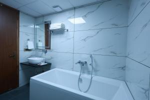 a white bathroom with a tub and a sink at RLS Hotels, Greater Noida Near Expo Centre & Mart in Greater Noida +85 photos