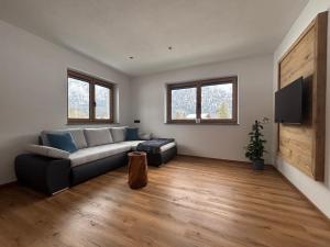 a living room with a couch and a tv at Haischberger Apartments in Obertraun