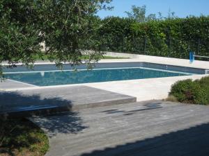 a swimming pool in a yard with a wooden deck at Maison d'Hôtes Le Clos de Bacchus in Julienne