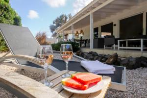 a table with two glasses of wine and a plate of fruit at Tropical villa Curoyal near the beach in Jan Thiel