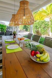 a wooden table with a plate of fruit on it at Tropical villa Curoyal near the beach in Jan Thiel +56 photos