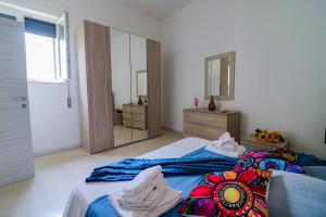 a bedroom with a bed with blue sheets and a mirror at Elaia's House in Cannole in Cannole