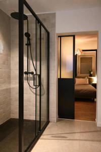 a bathroom with a glass door leading to a bed at L'Atelier de l'Émeraude in Saverne