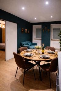 a dining room with a table with chairs and a couch at L'Atelier de l'Émeraude in Saverne